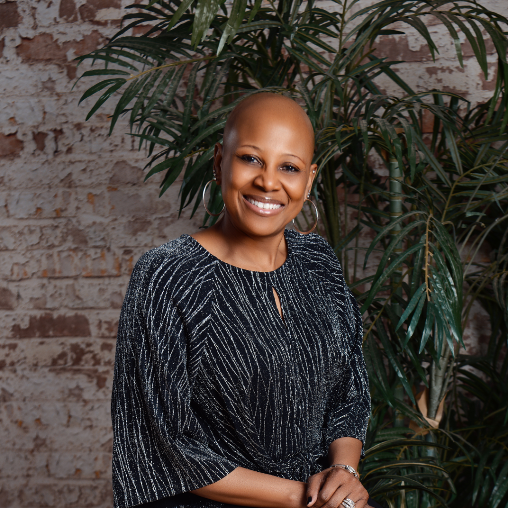 African American Women Headshot sitting on stool.